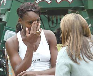 Venus Williams talks to the trainer before leaving the court for treatment
