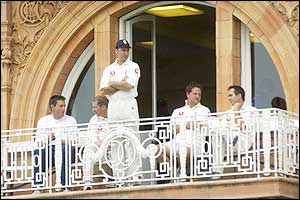 Some of the England team sit on the balcony at Lords as rain delays play