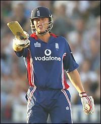 Andy Flintoff raises his bat to the crowd after reaching 50