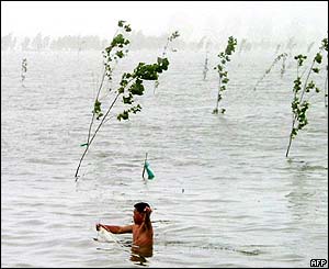 A man fishing in flood waters covering fields