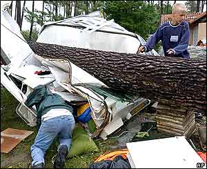 People sift through the debris of their trailer after it was crushed by a fallen tree at the La Rive campground 