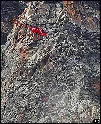 A helicopter lowers a worker to clear rock from a path on the Matterhorn