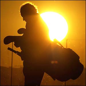 A caddie walks in front of the setting sun at Royal St George's