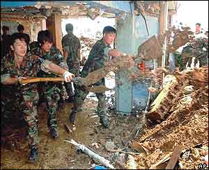 South Korean soldiers remove mud and debris brought inside a building by flood water in Busan