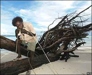 A man uses his teeth to split vines in order to make rope on Kennedy Island 