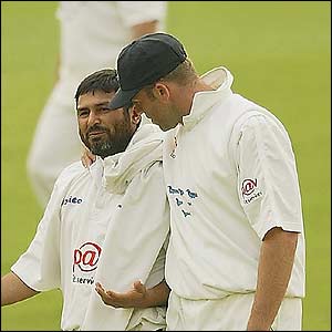 Sussex bowler Mushtaq Ahmed talks to captain Chris Adams 