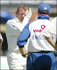 Alec Stewart holds his head after a ball bounces up and hits him on the side of the head