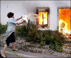 Woman throws pot of water at burning house 