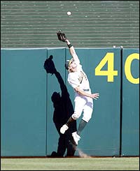 Eric Brynes of the Oakland A's tries to catch a ball hit by Ichiro Suzuki of the Seattle Mariners 