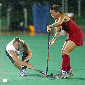 Canada's Andrea Rushton takes a shot in the pouring rain marked by America's Tracey Fuchs during the women's field hockey competition at the Parque Del Este in Santo Domingo