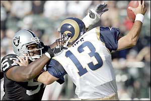 St Louis Rams' Hakim Akbar sacks Oakland Raiders quarter-back Kurt Warner in a pre-season friendly