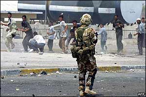 Iraqi youths aim rocks at a soldier