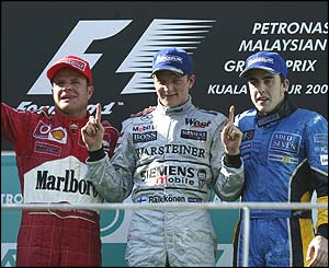 Malaysian Grand Prix winner Kimi Raikkonen is flanked on the podium by runner-up Rubens Barrichello and Fernando Alonso in third place
