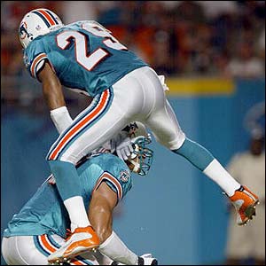 Sam Madison of the Miami Dolphins jumps on team-mate Jason Taylor