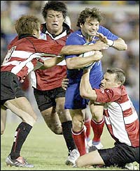 Japanese scrumhalf Yuji Sonoda, prop Ryo Yamamura and fly-half Andrew Miller tackle French winger Christophe Dominici
