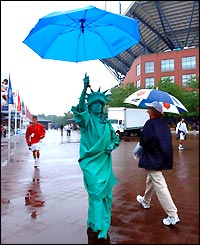 A tennis fan arrives at Flushing Meadows dressed as the Statue of Liberty and takes refuge under an umbrella