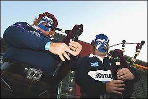 Scotland fans with painted faces play the bagpipes
