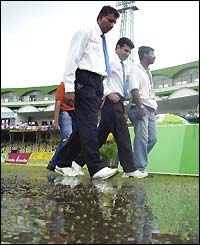 Umpires Ashoka de Silva and Aleem Dar leave the pitch with an official after an inspection in Dhaka