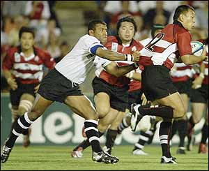 Yukio Motoki of Japan attempts to get away from the Fiji defence