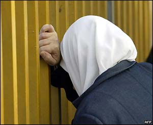 A woman bends her head on the fence of an Istanbul morgue 