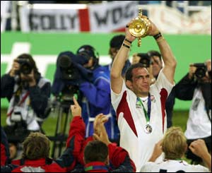 England skipper Martin Johnson lifts the William Webb Ellis trophy under the watchful eyes of the media