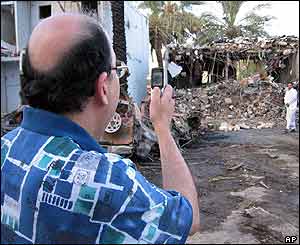 A resident of the complex takes a cellphone photo of the rubble of his neighbour's house 