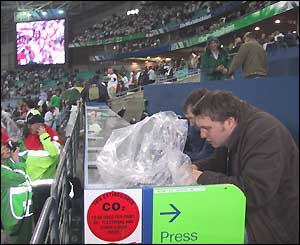 Press members work with their equipment protected from the rain by plastic sheets