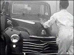 Garage mechanic pushing car with damaged bonnet