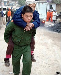 A firefighter evacuates an elderly resident from the area of the explosion 