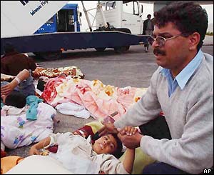 An Iranian man waits next to an injured child in Kerman airport, Iran