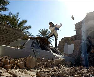 Mohammad Hussein Pourhamede clears stones from the top of a car in the ruins of his family's home