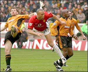 Dennis Irwin and Mikael Silvestre jump for a high ball in the Wolves area
