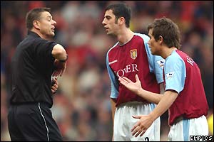 Referee Mike Halsey books Mark Delaney (centre) of Villa for protesting that the goal is allowed to stand