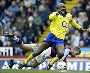 Patrick Vieira goes down on the edge of the penalty area after a challenge from Villa defender Olof Mellberg