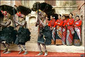 Indigenous dancers from Andhra Pradesh state perform as Assamese women look on, smiling.
