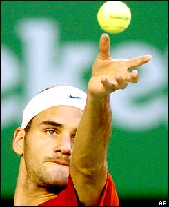 Roger Federer throws the ball up to serve