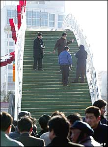 A crowd looks on as police take measurements on the bridge 