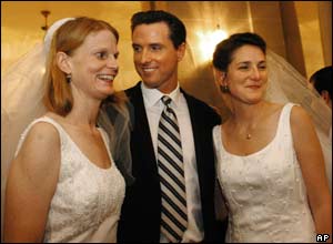 San Francisco Mayor Gavin Newsom stands between newlyweds Cissie Bonini (L) and Lora Pertle (R) during a reception at San Francisco City Hall