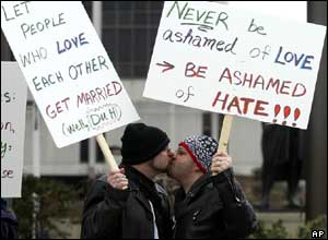 Christopher Hoffman (L) and Joshua Jacob Wiley (R) hold signs and kiss during a demonstration in favour of same-sex marriage