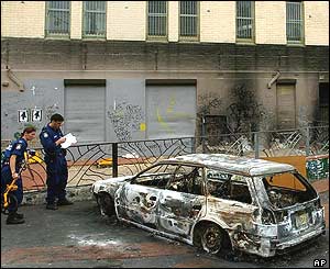 Police in Redfern inspect a burnt out car 