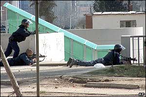 UNMIK police officers take cover near the bridge over the Ibar river, that divides the northern Serb-dominated part from the southern Albanian-dominated part of Mitrovica