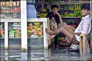 Flood affected shopkeepers sit in a waterlogged shop in Dhaka