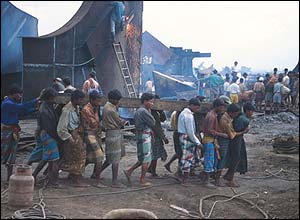 Workers carry a girder at Alang in India
