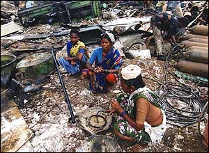 Three women sit in the midst of debris at Alang