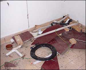 Rubble and a disused toilet seat on the floor of the gents' side of the toilet block