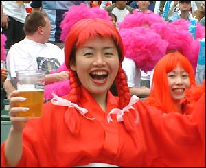 A fan wears a red kimono and wig whilst holding a pint of beer