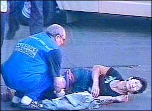 An emergency services worker talks to an injured woman lying on the ground