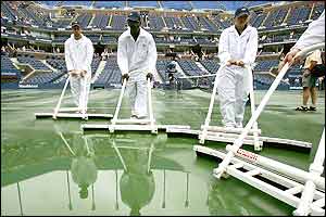 Workers mop up the rain on Arthur Ashe court