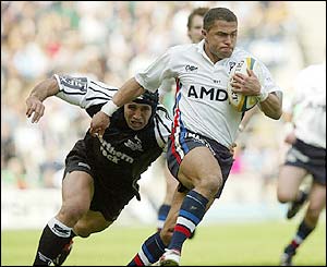 Jason Robinson of Sale Sharks gets past the tackle of Newcastle Falcon Mark Mayerhofler