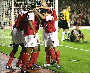 Arsenal players celebrate PSV's own goal